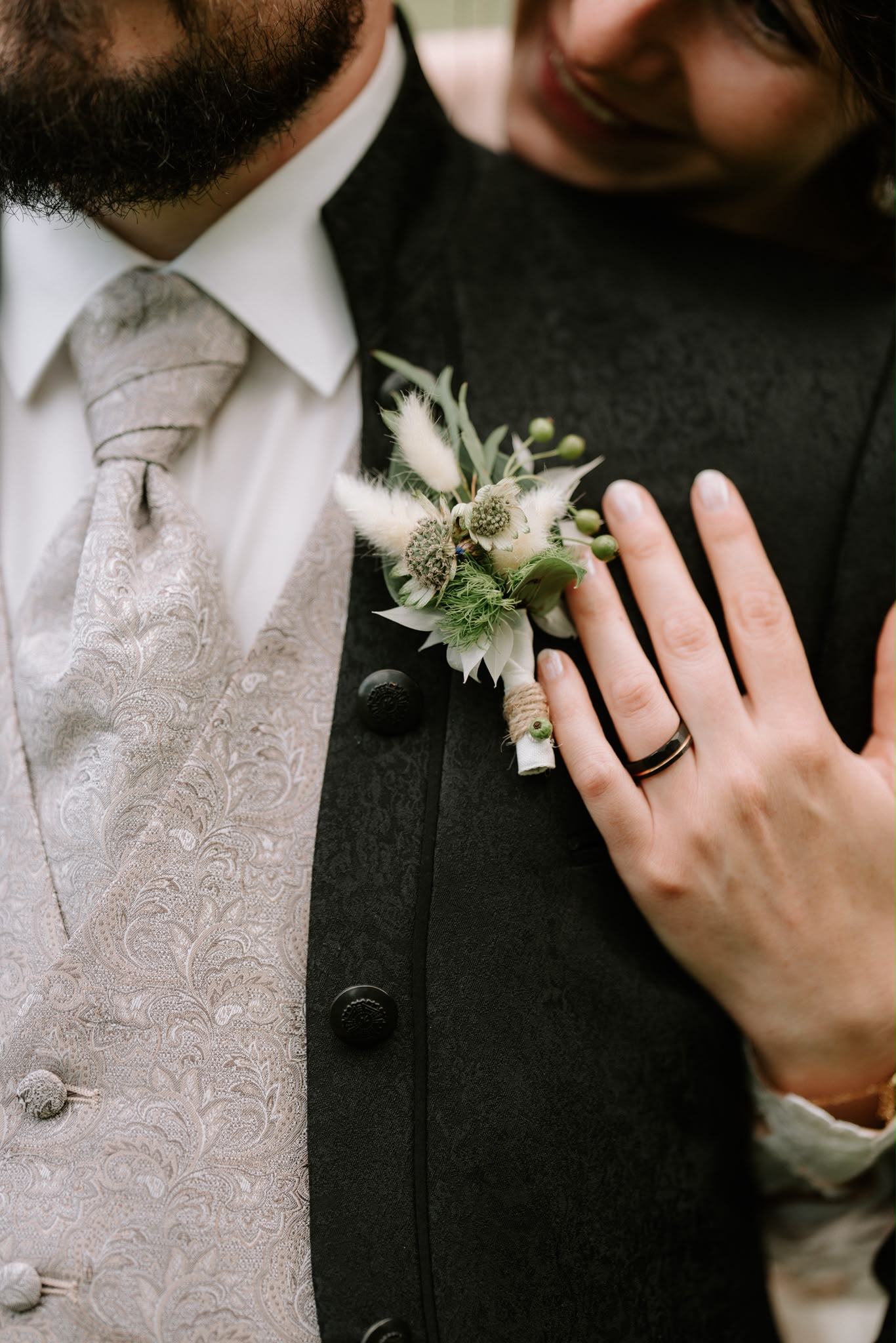 Floraler Hochzeitsanstecker mit weißen Blüten und Grün am Anzug des Bräutigams