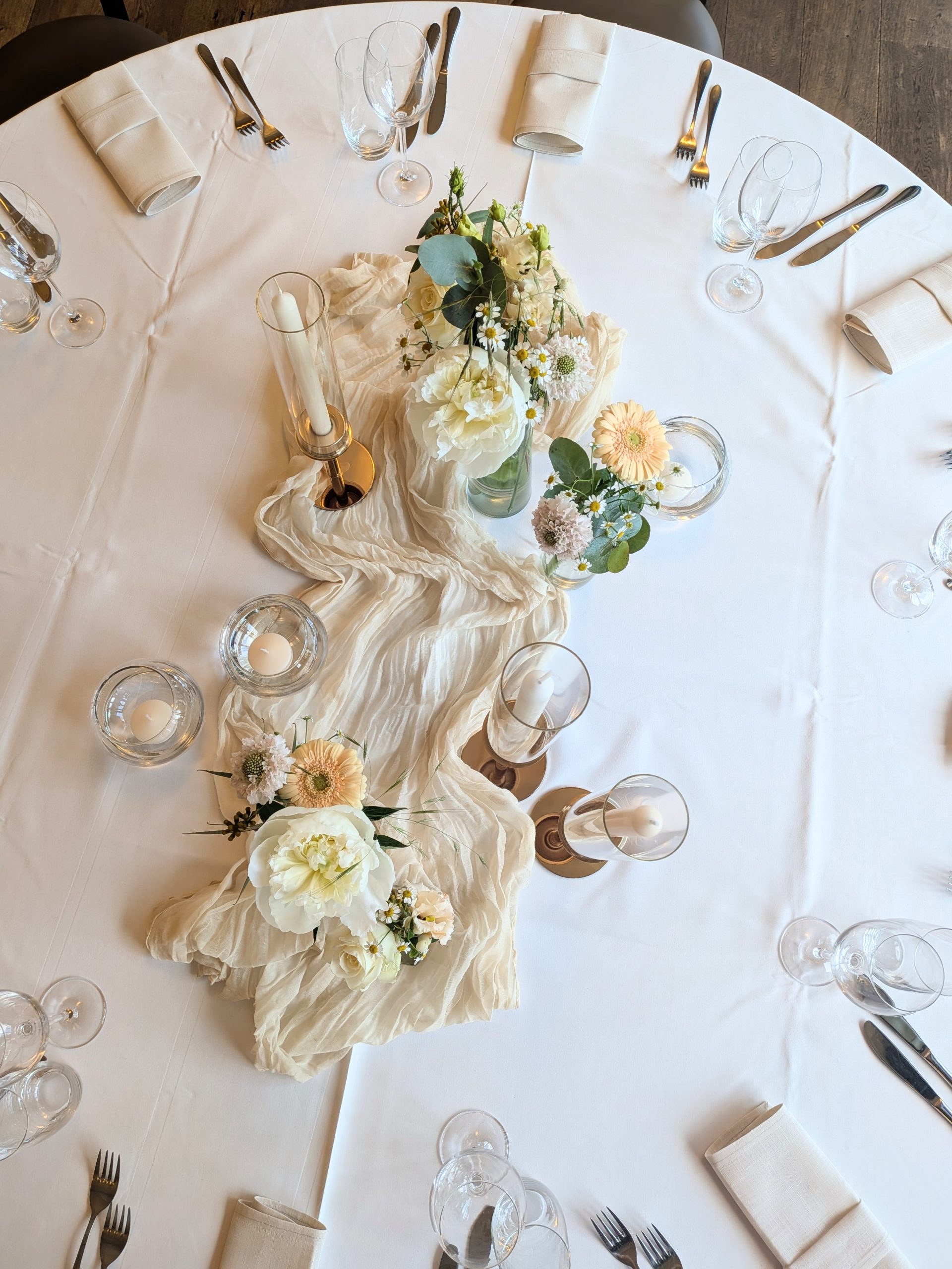 Florale Tischdekoration mit hellen Blumen, Kerzen und Eukalyptus für eine Hochzeit